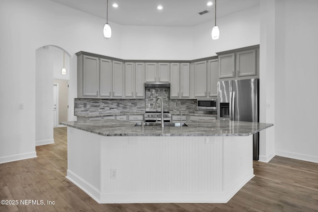 1506 Waterbridge Ct, Fleming Island, FL 32003 - kitchen with stainless steel appliances, arched walkways, gray cabinets, light stone counters, and recessed lighting