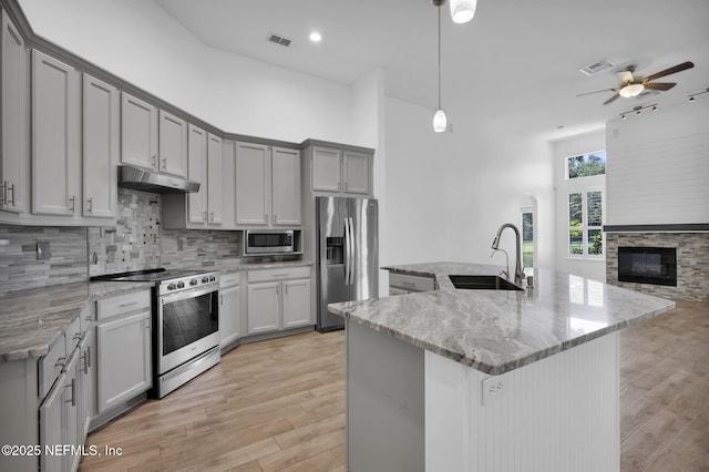 1506 Waterbridge Ct, Fleming Island, FL 32003 - kitchen with stainless steel appliances, under cabinet range hood, ceiling fan, light wood-style flooring, and light stone countertops