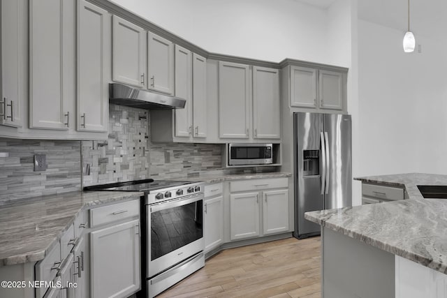 1506 Waterbridge Ct, Fleming Island, FL 32003 - kitchen with stainless steel appliances, under cabinet range hood, light wood finished floors, decorative backsplash, and light stone countertops