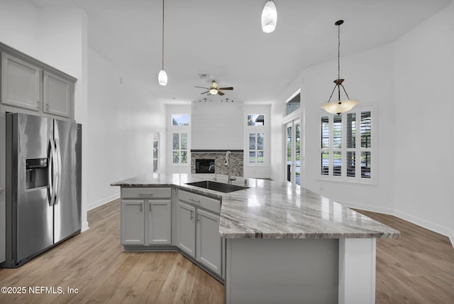 1506 Waterbridge Ct, Fleming Island, FL 32003 - kitchen featuring stainless steel fridge with ice dispenser, gray cabinets, a fireplace, light wood-type flooring, and open floor plan