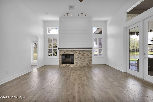 1506 Waterbridge Ct, Fleming Island, FL 32003 - unfurnished living room with a glass covered fireplace, hardwood / wood-style floors, a high ceiling, arched walkways, and a ceiling fan