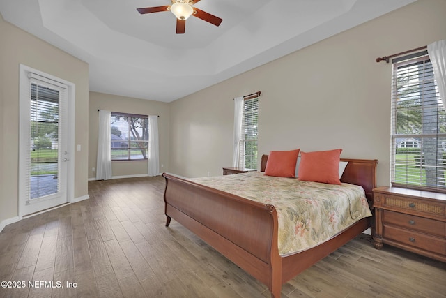 1506 Waterbridge Ct, Fleming Island, FL 32003 - bedroom featuring access to exterior, wood finished floors, ceiling fan, and a tray ceiling