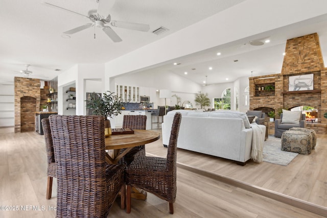 1465 Lambert Ave, Flagler Beach, FL 32136 - dining space with ceiling fan, a fireplace, light wood finished floors, recessed lighting, and vaulted ceiling