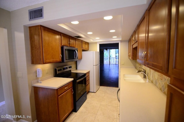 1810 Sevilla Blvd Unit 202, Atlantic Beach, FL 32233 - kitchen with range with electric cooktop, stainless steel microwave, freestanding refrigerator, light countertops, and brown cabinetry