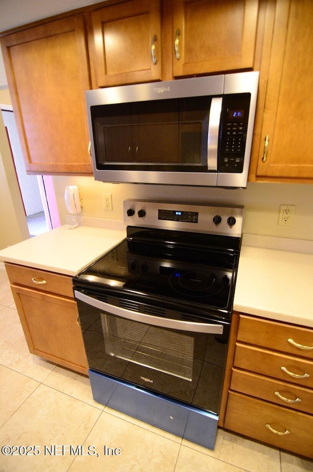1810 Sevilla Blvd Unit 202, Atlantic Beach, FL 32233 - kitchen with stainless steel appliances, light countertops, brown cabinetry, and light tile patterned floors