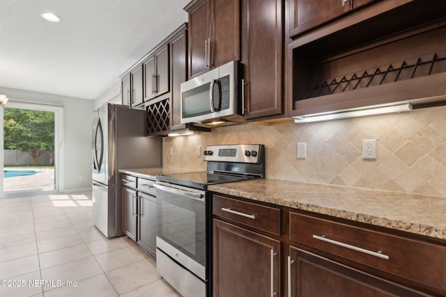 94032 Woodbrier Cir, Fernandina Beach, FL 32034 - kitchen featuring stainless steel appliances, light tile patterned floors, dark brown cabinetry, tasteful backsplash, and recessed lighting