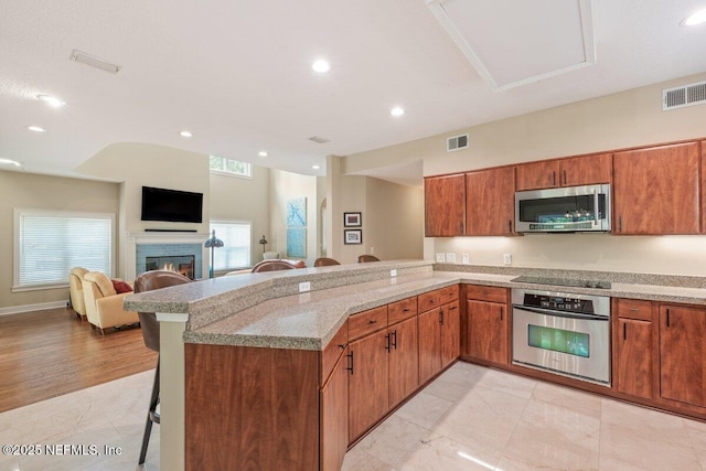2348 Seminole Reach Ct, Atlantic Beach, FL 32233 - kitchen featuring appliances with stainless steel finishes, a kitchen breakfast bar, a peninsula, brown cabinets, and recessed lighting