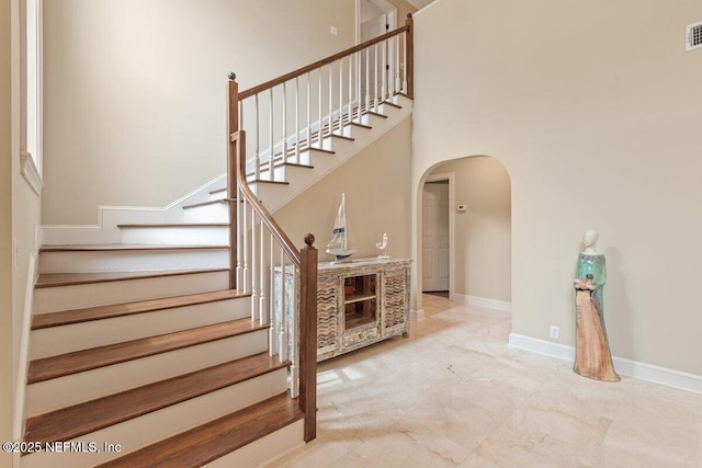 2348 Seminole Reach Ct, Atlantic Beach, FL 32233 - staircase featuring arched walkways, marble look tile flooring, and a towering ceiling