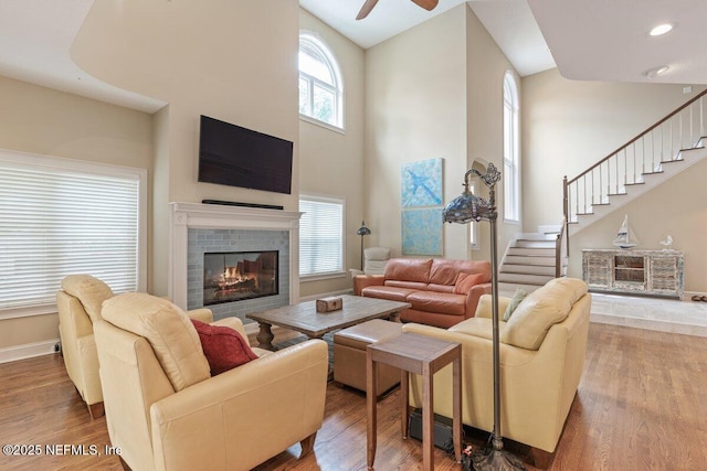 2348 Seminole Reach Ct, Atlantic Beach, FL 32233 - living room with a high ceiling, wood finished floors, a ceiling fan, a tiled fireplace, and stairway