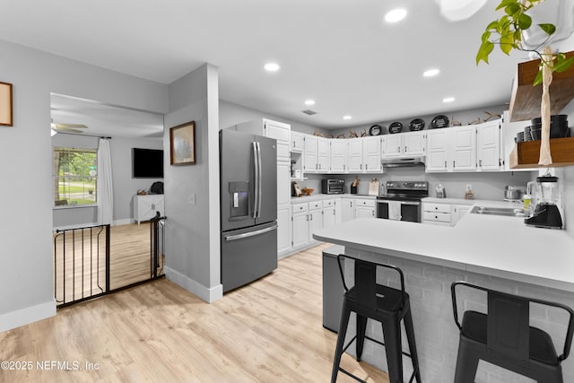 5263 Ellen Ct, Saint Augustine, FL 32086 - kitchen featuring appliances with stainless steel finishes, a peninsula, light countertops, white cabinets, and light wood-style flooring