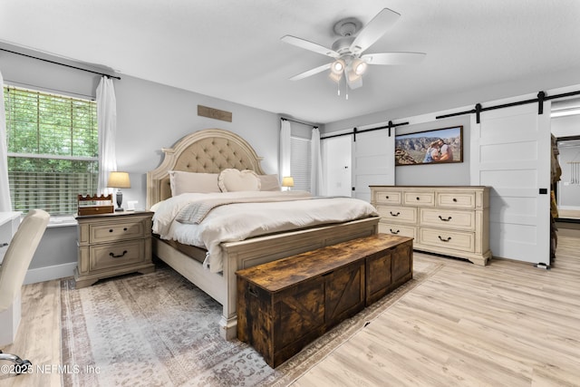 5263 Ellen Ct, Saint Augustine, FL 32086 - bedroom with a barn door, light wood-style floors, and a ceiling fan