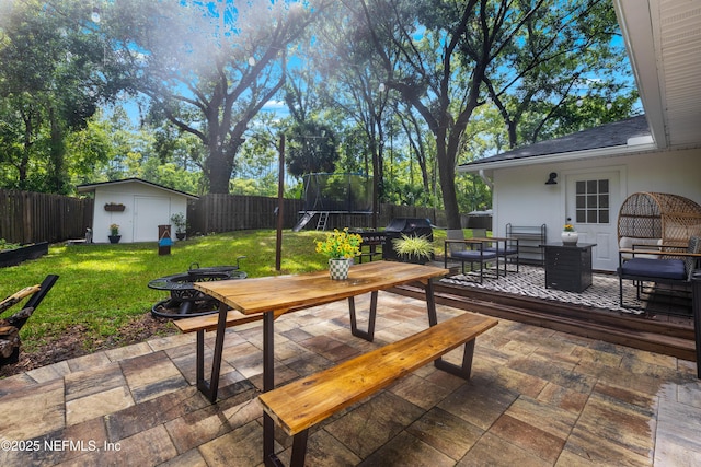 5263 Ellen Ct, Saint Augustine, FL 32086 - deck with outdoor dining space, a trampoline, a patio area, a fenced backyard, and a storage unit
