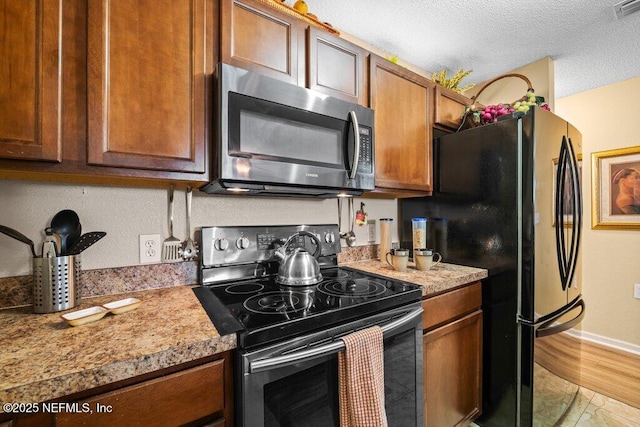 2548 Haywood Estates Ln, Jacksonville, FL 32233 - kitchen featuring stainless steel microwave, range with electric stovetop, freestanding refrigerator, light countertops, and a textured ceiling