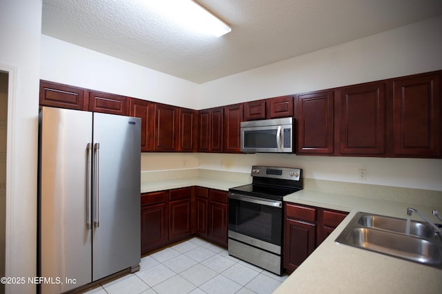 3600 Lenin Peak Ct Unit 8, Jacksonville, FL 32210 - kitchen featuring stainless steel appliances, reddish brown cabinets, light countertops, light tile patterned floors, and a textured ceiling