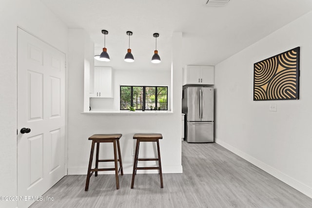 6285 Spring Forest Cir, Jacksonville, FL 32216 - kitchen featuring freestanding refrigerator, a kitchen bar, light wood-style floors, and white cabinetry