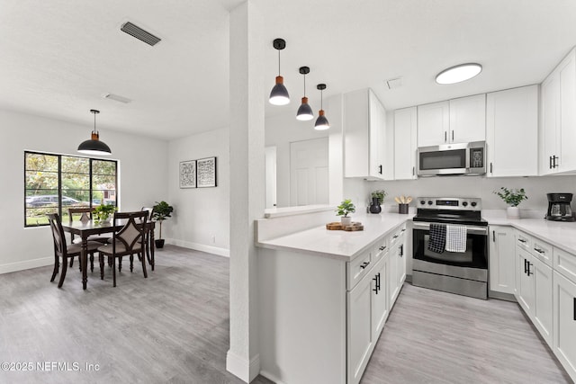 6285 Spring Forest Cir, Jacksonville, FL 32216 - kitchen featuring appliances with stainless steel finishes, light countertops, light wood finished floors, and white cabinetry