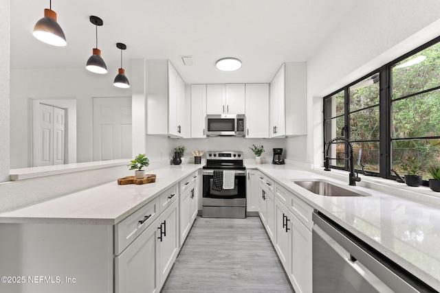 6285 Spring Forest Cir, Jacksonville, FL 32216 - kitchen with appliances with stainless steel finishes, white cabinets, light stone countertops, light wood finished floors, and pendant lighting