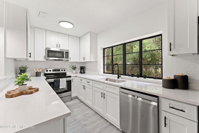 6285 Spring Forest Cir, Jacksonville, FL 32216 - kitchen with stainless steel appliances, white cabinets, light stone countertops, and light wood-style floors