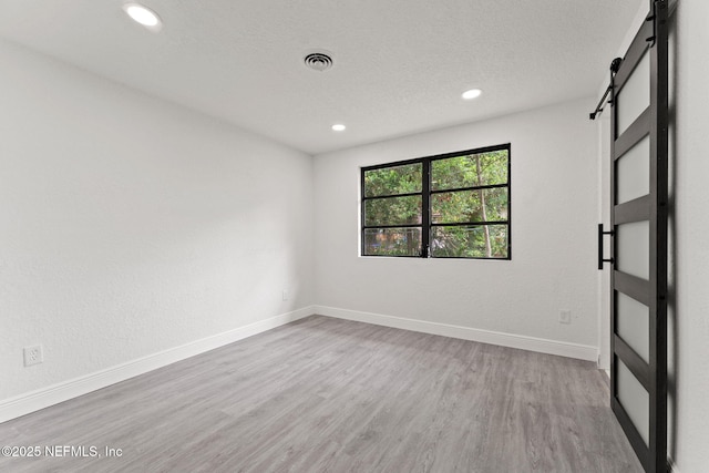 6285 Spring Forest Cir, Jacksonville, FL 32216 - spare room featuring a barn door, wood finished floors, recessed lighting, and a textured ceiling