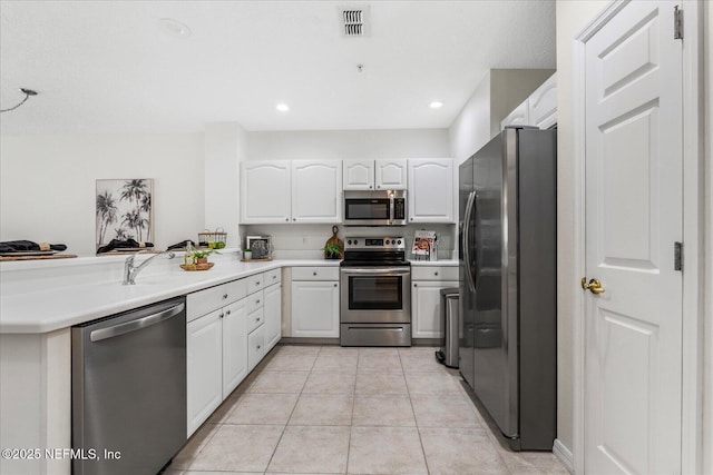 1200 Canopy Walk Ln Unit 1212, Palm Coast, FL 32137 - kitchen with appliances with stainless steel finishes, white cabinetry, light tile patterned flooring, a peninsula, and light countertops