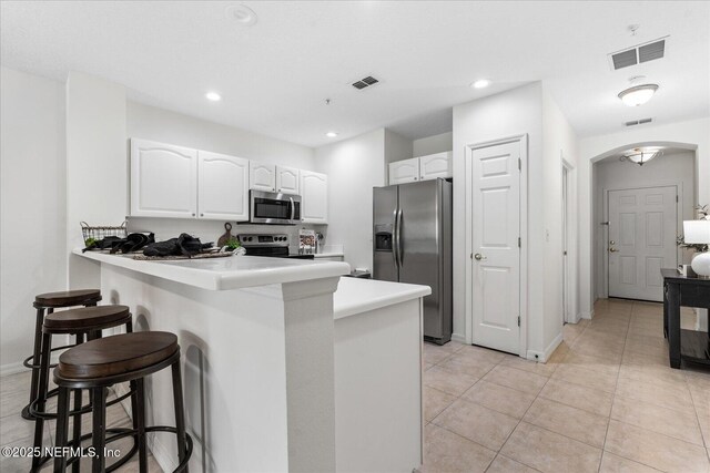 1200 Canopy Walk Ln Unit 1212, Palm Coast, FL 32137 - kitchen with stainless steel appliances, a kitchen bar, white cabinets, arched walkways, and recessed lighting