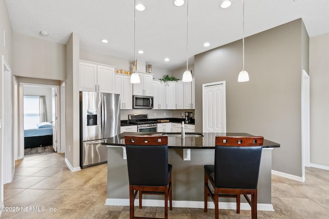 222 Green Turtle Ln, Saint Augustine, FL 32086 - kitchen featuring dark countertops, stainless steel appliances, a breakfast bar area, a center island with sink, and white cabinets