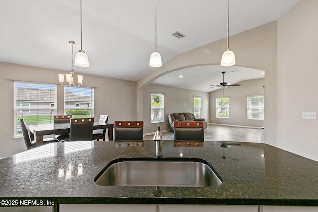 222 Green Turtle Ln, Saint Augustine, FL 32086 - kitchen with arched walkways, lofted ceiling, open floor plan, a chandelier, and dark stone countertops