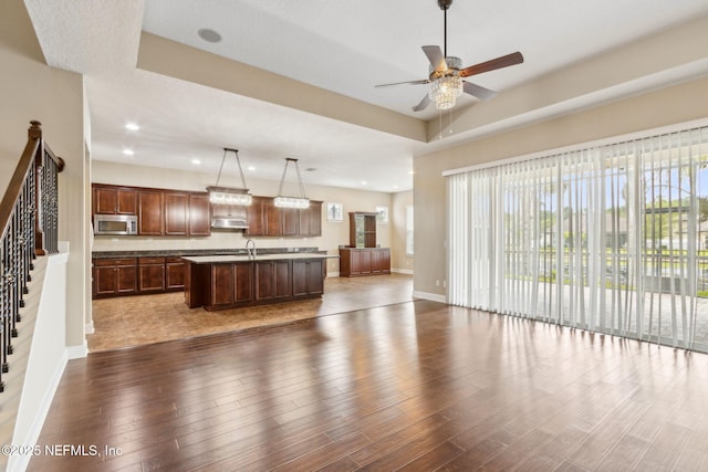 1306 Warbler Way, Middleburg, FL 32068 - kitchen featuring stainless steel microwave, open floor plan, a kitchen island with sink, dark wood-style flooring, and recessed lighting
