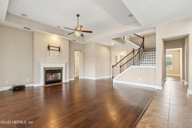 1306 Warbler Way, Middleburg, FL 32068 - unfurnished living room with a fireplace with flush hearth, stairway, ceiling fan, arched walkways, and wood-type flooring