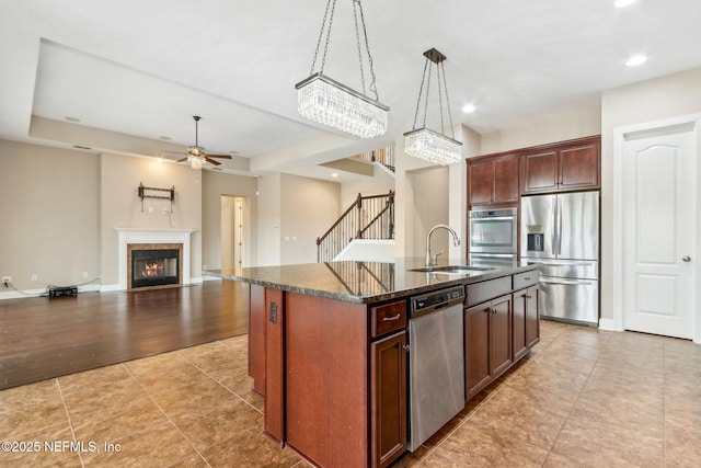 1306 Warbler Way, Middleburg, FL 32068 - kitchen with appliances with stainless steel finishes, a ceiling fan, an island with sink, dark stone counters, and open floor plan