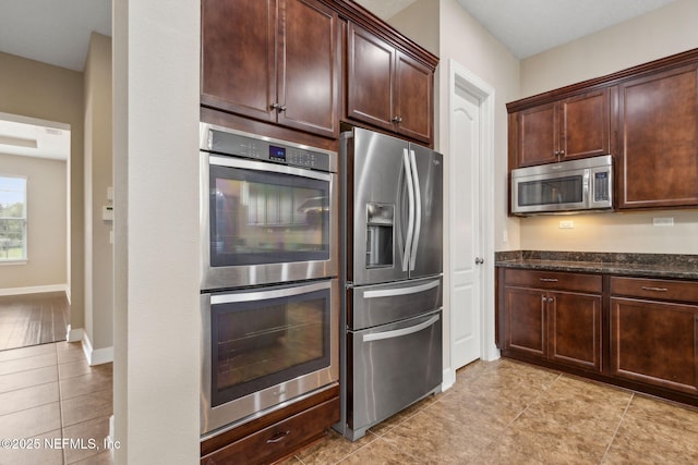 1306 Warbler Way, Middleburg, FL 32068 - kitchen featuring stainless steel appliances, light tile patterned flooring, dark brown cabinetry, and dark stone counters