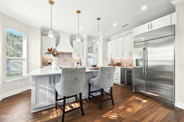 12490 Tropic Dr, Jacksonville, FL 32225 - kitchen featuring built in refrigerator, wine cooler, custom range hood, backsplash, and ornamental molding
