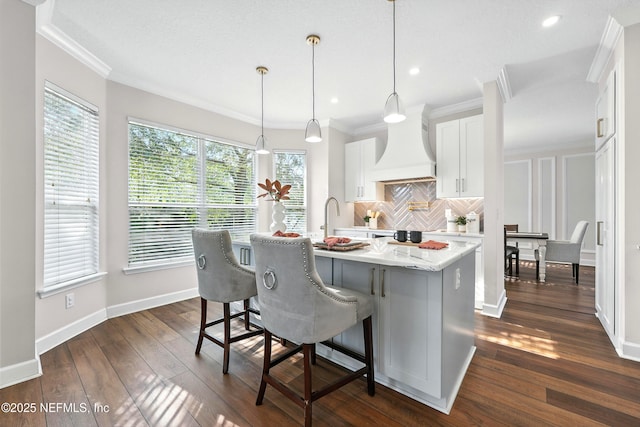 12490 Tropic Dr, Jacksonville, FL 32225 - kitchen with custom exhaust hood, white cabinets, backsplash, dark wood finished floors, and a center island with sink