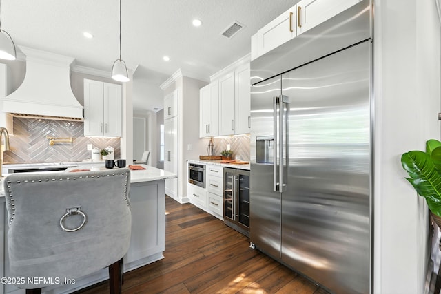 12490 Tropic Dr, Jacksonville, FL 32225 - kitchen with built in fridge, wine cooler, premium range hood, crown molding, and tasteful backsplash