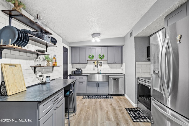 5414 Cleveland Rd, Jacksonville, FL 32209 - kitchen with appliances with stainless steel finishes, open shelves, gray cabinetry, tasteful backsplash, and a textured ceiling
