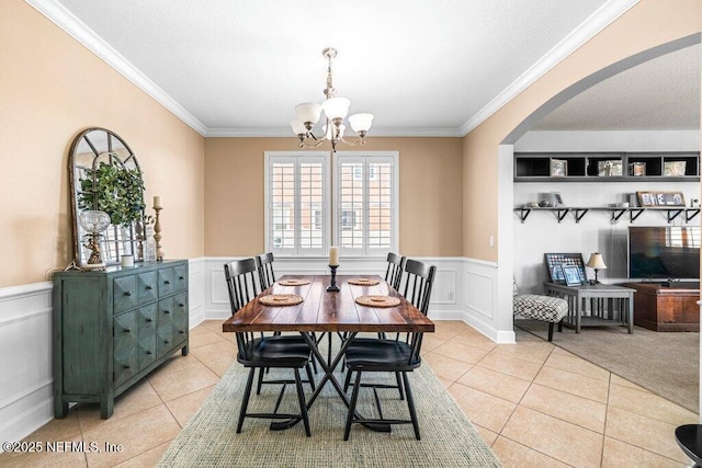11598 Wynnfield Lakes Cir, Jacksonville, FL 32246 - dining area with light tile patterned flooring, crown molding, a chandelier, arched walkways, and a decorative wall