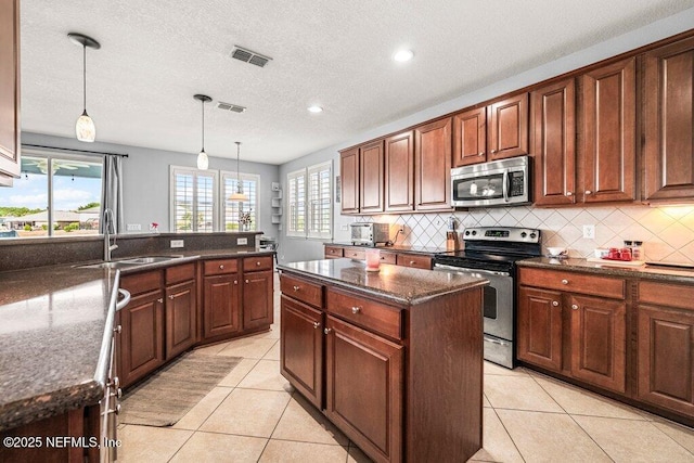 11598 Wynnfield Lakes Cir, Jacksonville, FL 32246 - kitchen featuring stainless steel appliances, backsplash, light tile patterned floors, hanging light fixtures, and recessed lighting