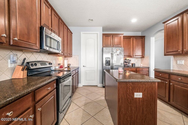 11598 Wynnfield Lakes Cir, Jacksonville, FL 32246 - kitchen featuring appliances with stainless steel finishes, a kitchen island, backsplash, dark stone countertops, and a textured ceiling