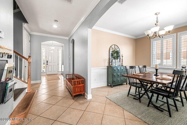 11598 Wynnfield Lakes Cir, Jacksonville, FL 32246 - dining area featuring arched walkways, light tile patterned floors, a chandelier, ornamental molding, and stairway