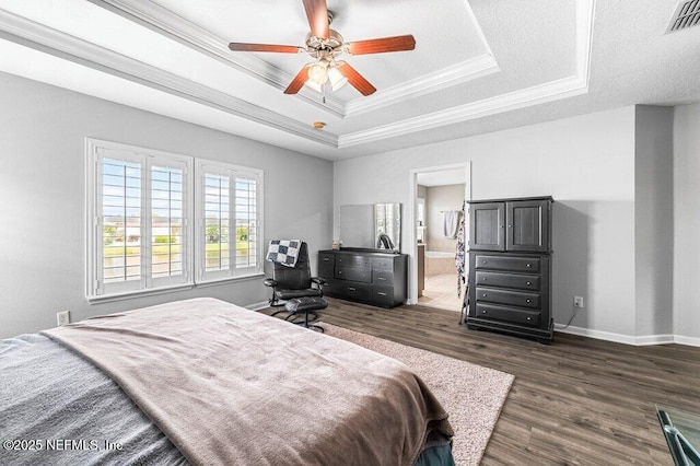 11598 Wynnfield Lakes Cir, Jacksonville, FL 32246 - bedroom with a tray ceiling, dark wood-type flooring, ornamental molding, a ceiling fan, and connected bathroom