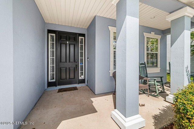 11598 Wynnfield Lakes Cir, Jacksonville, FL 32246 - doorway to property featuring covered porch and stucco siding