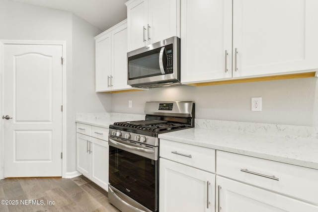 83687 Nether St, Fernandina Beach, FL 32034 - kitchen with stainless steel appliances, light wood finished floors, light stone counters, and white cabinets