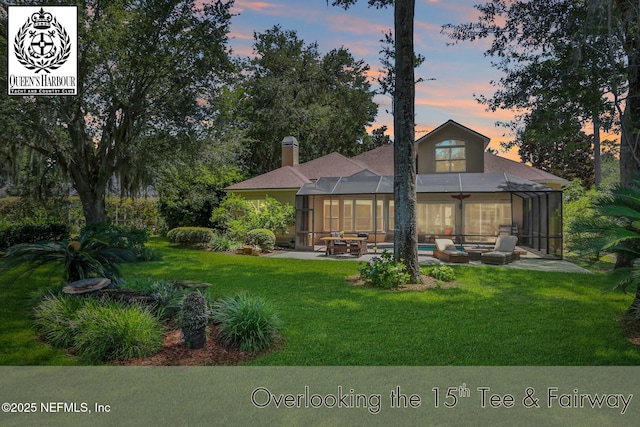 1521 Nottingham Knoll Dr, Jacksonville, FL 32225 - back of house at dusk featuring a patio, a lawn, an outdoor pool, glass enclosure, and a chimney