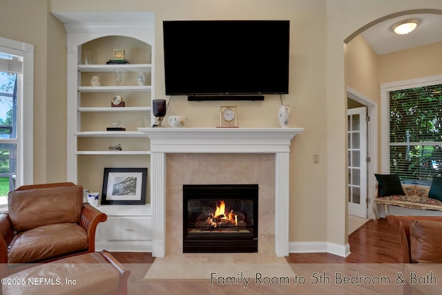 1521 Nottingham Knoll Dr, Jacksonville, FL 32225 - living room featuring a fireplace, built in features, wood finished floors, arched walkways, and plenty of natural light