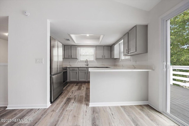 631-633 Main St, Atlantic Beach, FL 32233 - kitchen featuring gray cabinetry, stainless steel fridge, light wood-style floors, light countertops, and a peninsula