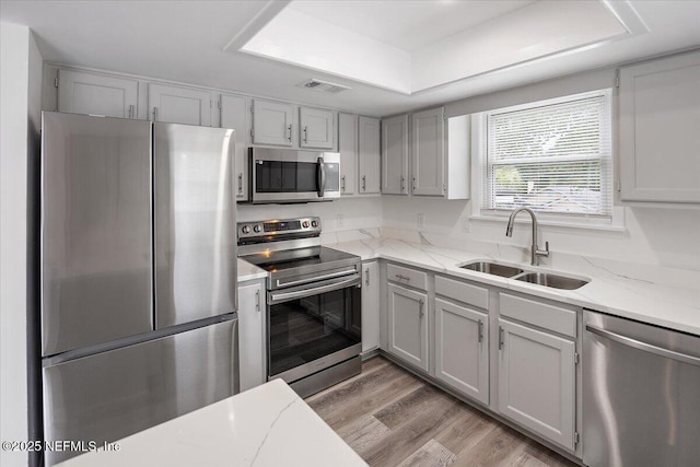 631-633 Main St, Atlantic Beach, FL 32233 - kitchen with stainless steel appliances, a tray ceiling, light stone countertops, and light wood-type flooring