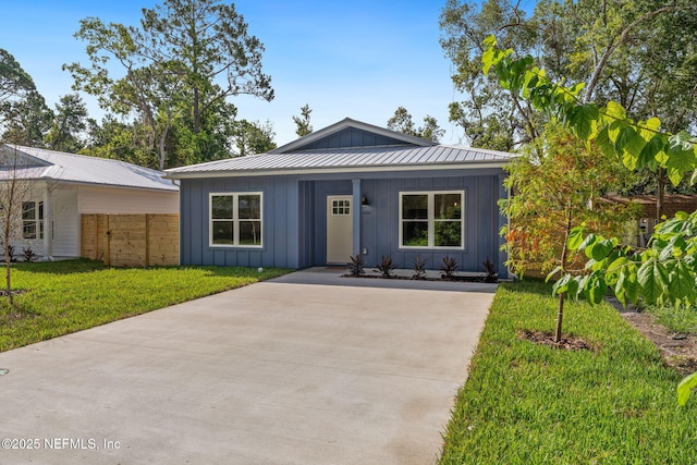 989 Butler Ave, Saint Augustine, FL 32084 - view of front of house with board and batten siding, a front yard, concrete driveway, and a metal roof