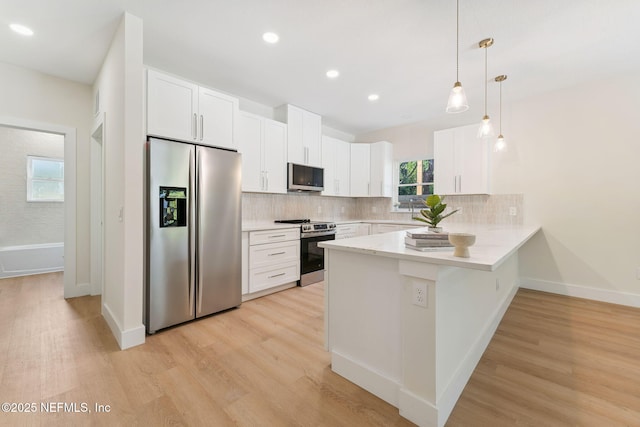 989 Butler Ave, Saint Augustine, FL 32084 - kitchen with appliances with stainless steel finishes, a peninsula, decorative backsplash, white cabinetry, and light wood finished floors