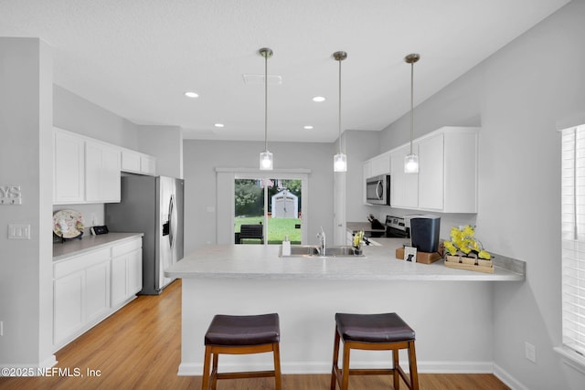 724 N Pine Ave, Green Cove Springs, FL 32043 - kitchen featuring stainless steel appliances, light wood-type flooring, a peninsula, white cabinetry, and light countertops