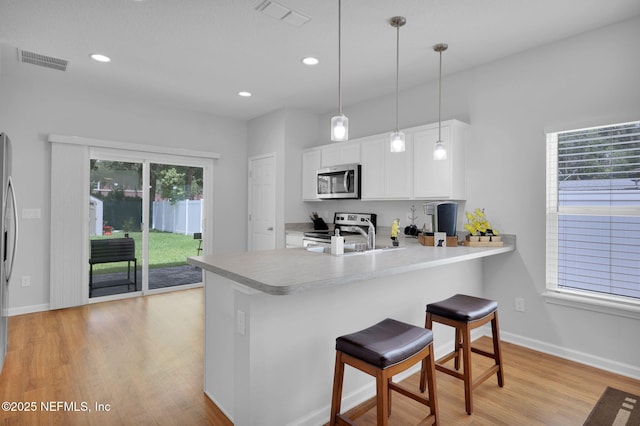724 N Pine Ave, Green Cove Springs, FL 32043 - kitchen featuring stainless steel appliances, light wood-style flooring, white cabinets, a peninsula, and light countertops
